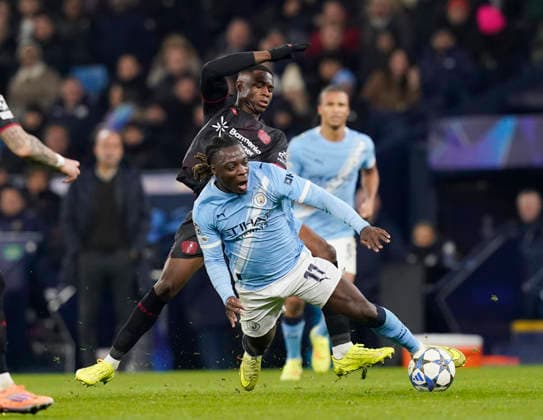 Manchester, England, 25th November 2025. Jeremy Doku of Manchester City fouled by Christian Kofane of Bayer Leverkusen during the Manchester City vs Bayer Leverkusen UEFA Champions League match at the Etihad Stadium, Manchester. Picture credit should read: Andrew Yates Sportimage EDITORIAL USE ONLY. No use with unauthorised audio, video, data, fixture lists, club league logos or live services. Online in-match use limited to 120 images, no video emulation. No use in betting, games or single club league player publications. SPI_064_AY_Man_City_Leverkusen SPI-4309-0094