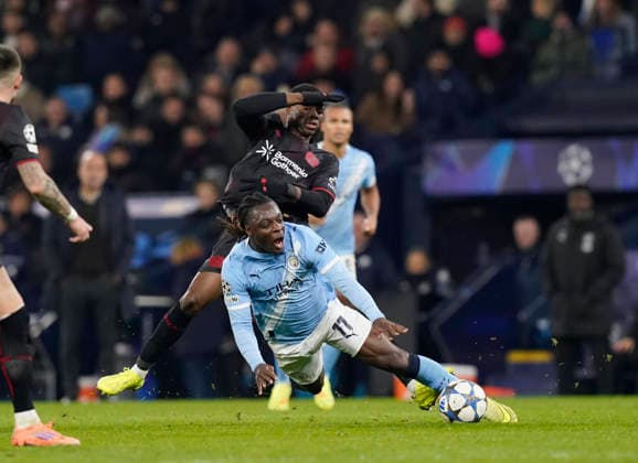 Manchester, England, 25th November 2025. Jeremy Doku of Manchester City fouled by Christian Kofane of Bayer Leverkusen during the Manchester City vs Bayer Leverkusen UEFA Champions League match at the Etihad Stadium, Manchester. Picture credit should read: Andrew Yates Sportimage EDITORIAL USE ONLY. No use with unauthorised audio, video, data, fixture lists, club league logos or live services. Online in-match use limited to 120 images, no video emulation. No use in betting, games or single club league player publications. SPI_065_AY_Man_City_Leverkusen SPI-4309-0095
