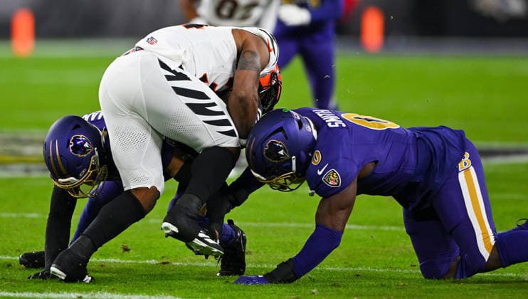 Baltimore Ravens safety Alohi Gilman (12) and inside linebacker Roquan Smith (0) tackle Cincinnati Bengals halfback Samaje Perine (34) during the first quarter at M&T Bank Stadium in Baltimore, Maryland, on Thursday, November 27 2025.  BAL20251127139 DAVIDxTULIS
