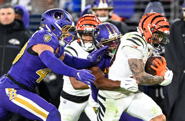 Cincinnati Bengals halfback Chase Brown (30) runs for a first down past Baltimore Ravens linebacker Teddye Buchanan (40) and cornerback Chidobe Awuzie (3) with blocking from Bengals wide receiver Mitchell Tinsley (C) during the fourth quarter at M&T Bank Stadium in Baltimore, Maryland, on Thursday, November 27 2025. Cincinnati won 32-14.  BAL20251127147 DAVIDxTULIS