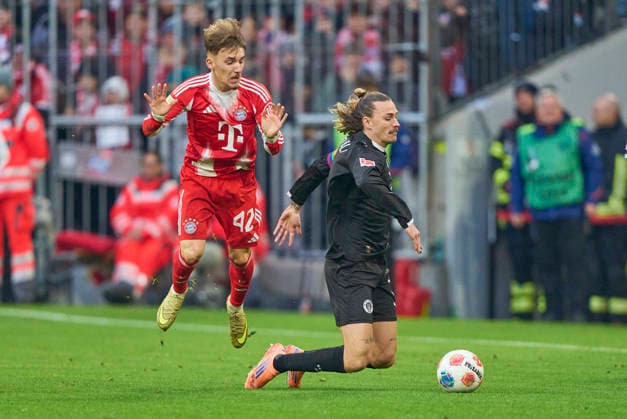 Lennart Karl of FC Bayern München compete for the ball, tackling, duel, header, zweikampf, action, fight against Jackson Irvine of St.Pauli in the match FC BAYERN MÜNCHEN - FC ST. PAULI on November 29, 2025 at Allianz Arena München, Germany. Season 2026 2026, 1.Bundesliga, FCB, matchday 12,