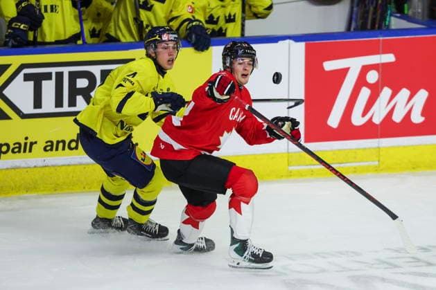 December 17, 2025, Kitchener, On, Canada: Canada s Carter Bear (12) tries to settle down a puck with pressure from Sweden s Linus Eriksson (14) during first period IIHF World Junior Hockey Championship pre-tournament action in Kitchener, Ont. on Wednesday, December 17, 2025. Canada News - December 17, 2025  - ZUMAc35_ 20251217_zaf_c35_037 Copyright: xNickxIwanyshynx