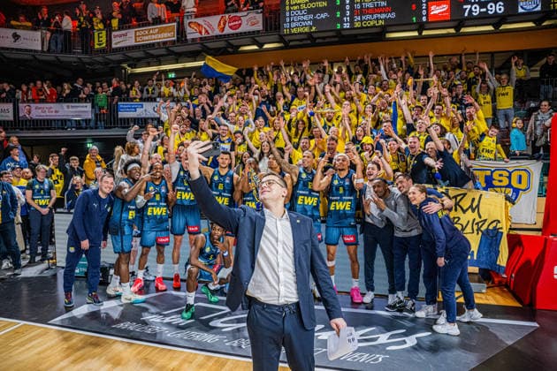 1 Basketball Bundesliga, easyCredit BBL, Season 2025 2026, Men, Main Round, Matchday 13, 29 12 2025, RASTA Vechta EWE Baskets Oldenburg Lazar Spasic Head Coach EWE Baskets Oldenburg at the victory selfie with the team and their fans Vechta RASTA Dome Lower Saxony Germany