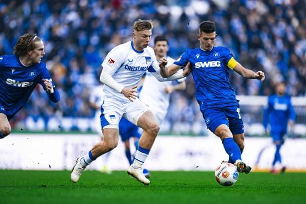 Marvin Wanitzek 10 Karlsruher SC with the ball, Sebastian Jung 2 Karlsruher SC defending against Kevin Sessa 8 Hertha BSC possession and tackle Copyright: xspeedshotx
