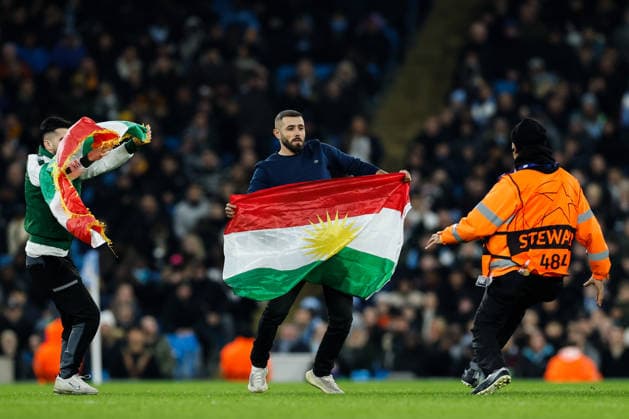Manchester, England, 28th January 2026. Pitch invaders hold up the Kurdistan flag during the Manchester City vs Galatasaray UEFA Champions League match at the Etihad Stadium, Manchester. Picture credit should read: Andrew Yates Sportimage EDITORIAL USE ONLY. No use with unauthorised audio, video, data, fixture lists, club league logos or live services. Online in-match use limited to 120 images, no video emulation. No use in betting, games or single club league player publications. SPI_040_CF_Man_City_Galatasaray SPI-4489-0097
