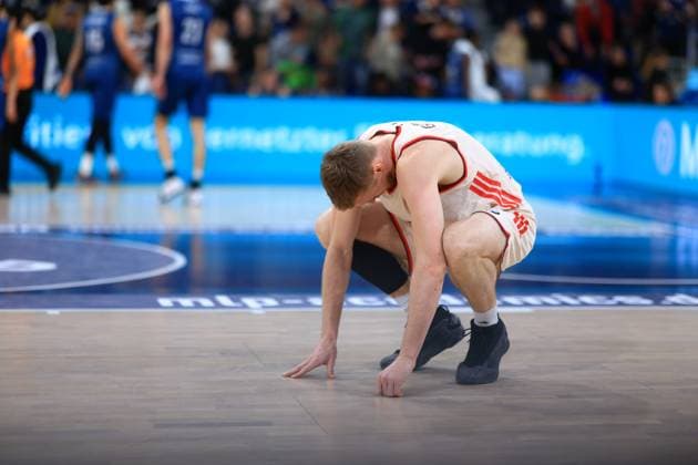 Basketball scene with a player in a white jersey kneeling on the court in the foreground easyCredit BBL MLP Academics Heidelberg - FC Bayern München Basketball 08 02 2026 Copyright: xMichaelxGelhardtx