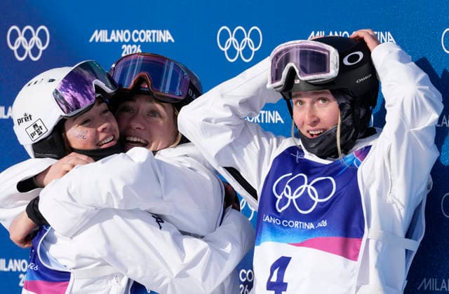 Jaelin Kauf (L) hugs teammate Tess Johnson as teammate Elizabeth Lemley looks at the board after the final scores were posted in the Women s Freestyle Skiing Moguls Finals at the Milano Cortina 2026 Winter Olympic Games, Olympische Spiele, Olympia, OS in Livigno, Italy, on Wednesday, February 11, 2026. Elizabeth Lemley of the United States won the gold medal, Jaelin Kauf of the United States won the silver medal and Perrine Laffont of France won the bronze medal.  OLY20260211864 BOBxSTRONG