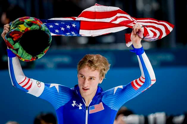 winner Jordan Stolz of United States of America celebrating and holding flag after Men 1000m, Milano Cortina 2026 Winter Olympics: Day 5, Speed skating, Eisschnelllauf - Milano Cortina 2026 Winter Olympics: Day 5, Milano Speed Skating Stadium, February 11, 2026, Milan, Italy.