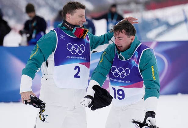 Gold medalist Cooper Woods of Australia (R) celebrates with teammate Matt Graham in the finish area after the Men s Freestyle Skiing Moguls competition at the Milano Cortina 2026 Winter Olympic Games, Olympische Spiele, Olympia, OS in Livigno, Italy, on Thursday, February 12, 2026. Mikael Kingsbury of Canada won the silver medal and Ikuma Horishima of Japan won the bronze medal.  OLY20260212810 BOBxSTRONG