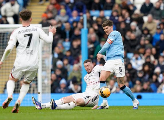 Manchester, England, 14th February 2026. Ryan Graydon of Salford City tackled by John Stones of Manchester City during the Manchester City vs Salford City FA Cup fourth round match at the Etihad Stadium, Manchester. Picture credit should read: Andrew Yates Sportimage EDITORIAL USE ONLY. No use with unauthorised audio, video, data, fixture lists, club league logos or live services. Online in-match use limited to 120 images, no video emulation. No use in betting, games or single club league player publications. SPI_035_AY_Man_City_Salford SPI-4533-0037