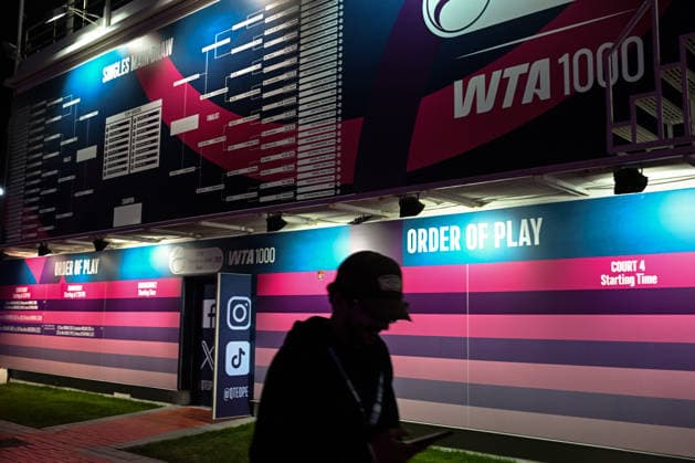 Doha Racket Exchange: WTA, Tennis Damen 1000 Finale Gives Way To ATP, Tennis Herren 500 Arrivals DOHA, QATAR FEBRUARY 14: A silhouette of a tournament staff member walking past the official singles main draw and order of play boards during the final night of the 2026 Qatar TotalEnergies Open at the Khalifa International Tennis and Squash Complex in Doha, Qatar, February 14, 2026. The evening marks a major logistical transition at the venue as the WTA 1000 event concludes and the site prepares for the arrival of the ATP 500 Qatar ExxonMobil Open tour with early practice sessions and media preparations Doha Qatar  Copyright: xArturxWidakx originalFilename:widak-doharack260214_npoly.jpg