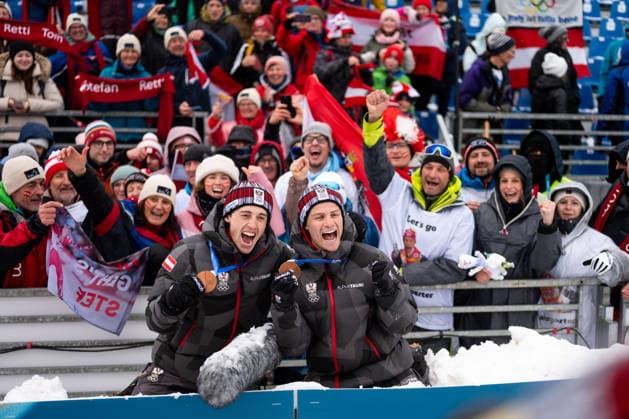 RETTENEGGER Stefan (Oesterreich), LAMPARTER Johannes (Oesterreich) jubeln mit den Fans Zuschauern ueber Platz 3 und die Bronze Medaille, ITA, Olympische Spiele Milano Cortina 2026, Olympia, Nordische Kombination, Teamsprint, 2 x 7,5 km Langlauf, 19.02.2026 ITA, Olympische Spiele Milano Cortina 2026, Olympia, Nordische Kombination, Teamsprint, 2 x 7,5 km Langlauf, 19.02.2026 Tesero *** RETTENEGGER Stefan Oesterreich , LAMPARTER Johannes Oesterreich cheer with the fans spectators about 3rd place and the bronze medal, ITA, Olympic Games Milano Cortina 2026, Olympic Games, Nordic Combined, Team Sprint, 2 x 7.5 km Cross-Country Skiing, 19 02 2026 ITA, Olympic Games Milano Cortina 2026, Olympic Games, Nordic Combined, Team Sprint, 2 x 7.5 km Cross-Country Skiing, 19 02 2026 Tesero Copyright: xEibner-Pressefoto Memmlerx EP_MMR