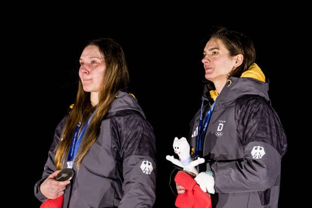 CORTINA, ITALY - FEBRUARY 21: Silver medalists Lisa Buckwitz Neele Schuten (Germany) during the anthem during the Bobsleigh 2-woman medal ceremony at the Milano Cortina 2026 Olympics at Cortina Sliding Centre on day 15 of the Milano Cortina 2026 Olympics on February 21, 2026 in Cortina, Italy. Editorial use only. Italy Copyright: xSteffiexWunderlx