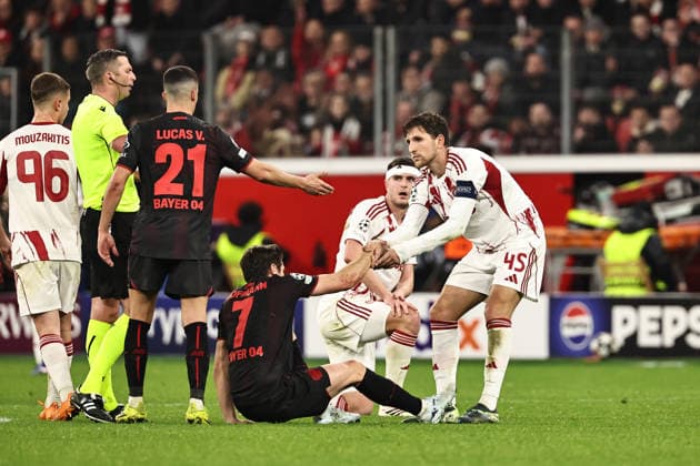 GER, Champions League, Bayer Leverkusen vs Olympiakos Piraeus 24 02 2026, BayArena, Leverkusen, GER, Champions League, Bayer Leverkusen vs Olympiakos Piraeus in the picture Captain Panagiotis Retsos Olympiakos Piraeus, 45, white helps Jonas Hofmann Bayer 04 Leverkusen, 07, black back on his feet under the eyes of referee Michael Oliver England nordphotoxGmbHx xSJS nph00070
