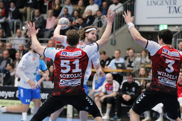 25 02 2026 Handball Men 2025 2026 2 Handball Bundesliga 21 Matchday HSG Nordhorn Lingen Dessau Roßlauer HV 06 EmslandArena Lingen Mika Schüler Dessau, 23, white throwing Luka Sokolic Nordhorn, 51, red and Christian Wilhelm Nordhorn, 3, red try the block Lingen Ems Lower Saxony Germany