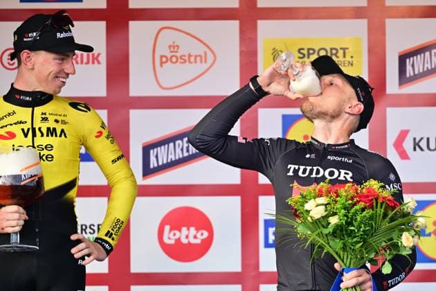 Winner Great Britain s Matthew Brennan of Team Visma-Lease a Bike looks at Italy s Matteo Trentin of Tudor Pro Cycling Team drinking his Kwaremont beer ad fundum on the podium of the 78th edition of the men elite race of the Kuurne-Brussels-Kuurne one day cycling race, 195 km from Kuurne to Kuurne via Brussels, Sunday 01 March 2026. DIRKxWAEM  x166108448x