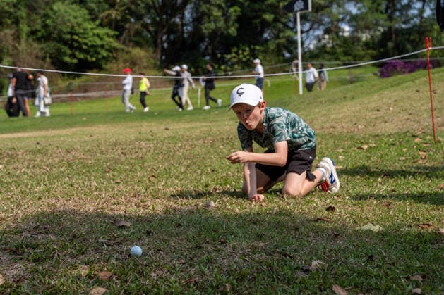 HONGKONG LIV-GOLF A boy points at a golf ball on the grass in Fanling Golf Course where LIV Golf Hong Kong is being held in Hong Kong, March 7, 2026. NEXPHER Vernon Yuen HONG KONG