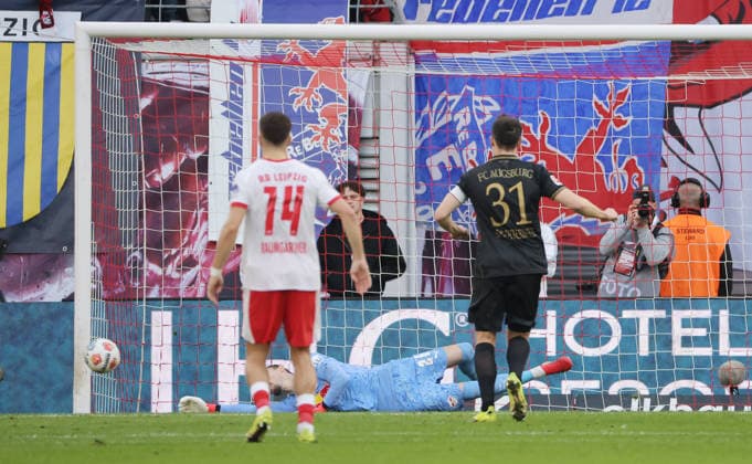 Keven Schlotterbeck shoots penalty kick against goalkeeper Maarten Vandevoordt parries duel Game scene Action Sport Soccer Football DFL Bundesliga Men 25 Matchday Season 2025 2026 07 03 2026 RasenBallsport RB Leipzig RBL vs FC Augsburg FCA at RedBull Arena DFL regulations prohibit any use of photographs as image sequences and or quasi video