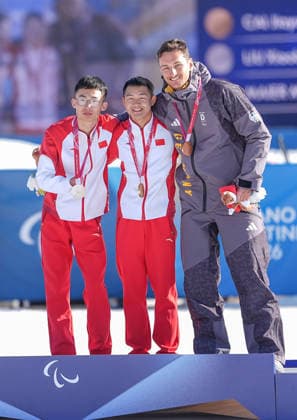 (260308) -- TESERO, March 8, 2026 -- Gold medalist Cai Jiayun (C) of China celebrates on the podium alongside silver medalist Liu Xiaobin (L) of China and bronze medalist Marco Maier of Germany during the awarding ceremony for the para biathlon men s sprint at the Milan-Cortina 2026 Paralympic Winter games, Winterspiele,Spiele, Summer games in Tesero, Italy, March 7, 2026. ) (SP)ITALY-TESERO-PARALYMPIC WINTER GAMES-PARA BIATHLON-MEN S SPRINT STANDING HouxZhaokang 