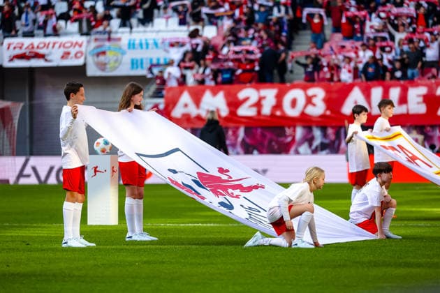 Children holding the flags with the Verins logo at the run-in, RB Leipzig vs FC Augsburg, Football, 1 Bundesliga, 25 Matchday, Season 2025 2026, 07 03 2026,¨ DFL REGULATIONS PROHIBIT ANY USE OF PHOTOGRAPHS AS IMAGE SEQUENCES AND OR QUASI VIDEO,¨ RB Leipzig vs FC Augsburg, Football, 1 Bundesliga, 25 Matchday, Season 2025 2026, 07 03 2026 Leipzig Copyright: xEibner-Pressefoto LauraxRoemerx EP_LRR