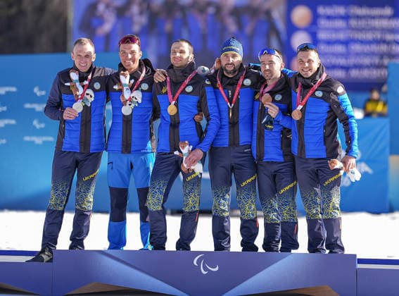 (260308) -- TESERO, March 8, 2026 -- Gold medalist Oleksandr Kazik (3rd L) of Ukraine and guide Serhii Kucheriavyi (3rd R) celebrate on the podium alongside silver medalist Iaroslav Reshetynskyi (1st L) of Ukraine and guide Dmytro Drahun (2nd L) and bronze medalist Anatolii Kovalevskyi (2nd R) of Ukraine and guide Oleksandr Mukshyn during the awarding ceremony for the para biathlon men s sprint Vision Impaired at the Milan-Cortina 2026 Paralympic Winter games, Winterspiele,Spiele, Summer games in Tesero, Italy, March 7, 2026. ) (SP)ITALY-TESERO-PARALYMPIC WINTER GAMES-PARA BIATHLON-MEN S SPRINT VISION IMPAIRED HouxZhaokang 