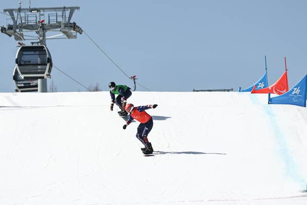 ITALY, VENETO - MARCH 8, 2026: Mike Schultz (front) and Noah Elliott of the US compete during the men s para snowboard snowboard cross SB-LL1 event at Cortina Para Snowboard Park during the 2026 Winter Paralympic Games. Mikhail Tereshchenko TASS  89753853