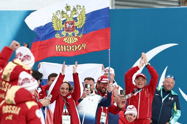 ITALY, TESERO - MARCH 11, 2026: Fans of Russia attend a victory ceremony for the men s para cross-country skiing 10km interval start sitting at Tesero Cross-Country Stadium during the 2026 Winter Paralympic Games. Mikhail Tereshchenko TASS  89886986