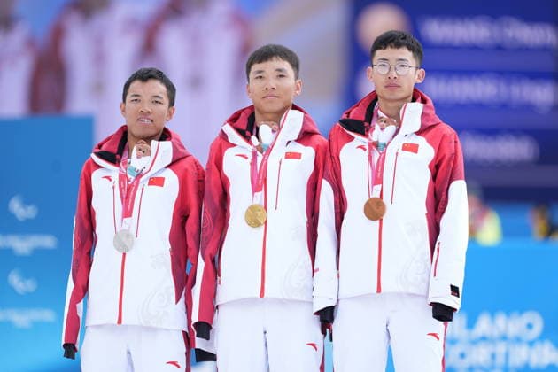 (260315) -- TESERO, March 15, 2026 -- Gold medalist Wang Chenyang (C), silver medalist Huang Lingxin (L), bronze medalist Liu Xiaobin of China pose during the awarding ceremony for the para cross-country skiing men s 20km interval start free standing at the Milan-Cortina 2026 Paralympic Winter games, Winterspiele,Spiele, Summer games in Tesero, Italy, March 15, 2026. ) (SP)ITALY-TESERO-PARALYMPIC WINTER GAMES-PARA CROSS-COUNTRY SKIING-MEN S 20KM INTERVAL START FREE STANDING HouxZhaokang 