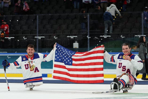 March 15, 2026, Milan, Lombardy, Italy: BRODY ROYBAL 4 and JACK WALLACE 8 of Team USA celebrate with the flag of United States of America after winning the gold medal in the Final game between Team United States (USA) and Team Canada (CAN) at the Milano Cortina 2026 Paralympic Winter games, Winterspiele,Spiele, Summer games Team USA won 6:2 and their fifth consecutive Para Ice hockey, Eishockey Milan Italy - ZUMAc179 20260315_oly_c179_127 Copyright: xMickaelxChavetx