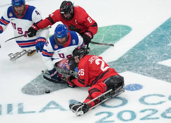 (260316) -- MILAN, March 16, 2026 -- Declan Farmer (C) of the United States vies with Anton Jacobs-Webb of Canada during the Para Ice hockey, Eishockey final match between the United States and Canada at the Milan-Cortina 2026 Paralympic Winter games, Winterspiele,Spiele, Summer games in Milan, Italy, March 15, 2026. ) (SP)ITALY-MILAN-CORTINA 2026-PARALYMPIC WINTER GAMES-PARA ICE HOCKEY-USA VS CANADA LixJing 