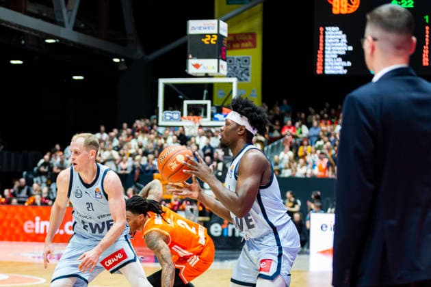 28 03 2026, xomx, Basketball easyCredit BBL Bundesliga, NINERS Chemnitz EWE Baskets Oldenburg v l Seth Hinrichs EWE Baskets Oldenburg , Nike Sibande Niners Chemnitz and Brian Fobbs EWE Baskets Oldenburg in front of Lazar Spasic EWE Baskets Oldenburg Head Coach Coach in the fight for the ball Chemnitz