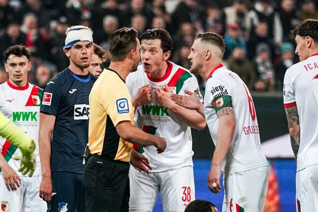 Fussball: Deutschland: 1. Bundesliga 2025 2026 - 29. Spieltag, 10.04.2026 - FC Augsburg vs. TSG Hoffenheim - WWK Arena (Augsburg, Deutschland); Diskussionen zwischen Schiedsrichter Daniel Schlager, Michael Gregoritsch (FC Augsburg), Jeffrey Gouweleeuw (FC Augsburg) *** Soccer Germany 1 Bundesliga 2025 2026 Matchday 29, 10 04 2026 FC Augsburg vs TSG Hoffenheim WWK Arena Augsburg, Germany Discussions between referee Daniel Schlager, Michael Gregoritsch FC Augsburg , Jeffrey Gouweleeuw FC Augsburg Copyright: xLUKAxKOLANOVICx