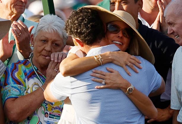 Rory McIlroy of Northern Ireland celebrates with his wife Erica Stoll McIlroy as his mother Rosie (L) looks on after winning the 2026 Masters Tournament at Augusta National Golf Club on Sunday, April 12, 2026, in Augusta, Georgia. McIlroy won his second consecutive Masters with a 12-under-par four-day score of 276.  AUG20260412903 JOHNxANGELILLO