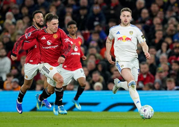 Manchester, England, 13th April 2026. Gabriel Gudmundsson of Leeds United with the ball under pressure from Manuel Ugarte of Manchester United, ManU during the Manchester United vs Leeds United Premier League match at Old Trafford, Manchester. Picture credit should read: Andrew Yates Sportimage EDITORIAL USE ONLY. No use with unauthorised audio, video, data, fixture lists, club league logos or live services. Online in-match use limited to 120 images, no video emulation. No use in betting, games or single club league player publications. SPI_064_AY_Man_Utd_Leeds SPI-4684-0064