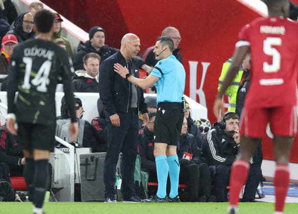 Liverpool, England, 14th April 2026. Arne Slot manager of Liverpool is spoken to by referee Maurizio Mariani during the Liverpool vs Paris Saint Germain UEFA Champions League quarter final 2nd leg match at Anfield, Liverpool. Picture credit should read: Jessica Hornby Sportimage EDITORIAL USE ONLY. No use with unauthorised audio, video, data, fixture lists, club league logos or live services. Online in-match use limited to 120 images, no video emulation. No use in betting, games or single club league player publications. SPI_070_JH_Liverpool_PSG SPI-4687-0070