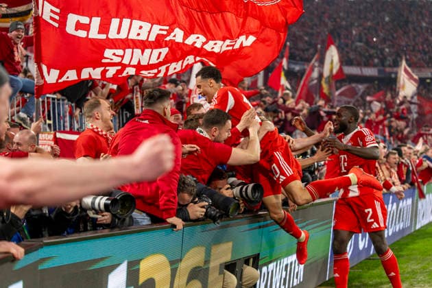15 04 2026, Football UEFA Champions League 2025 2026 quarter-final second leg, FC Bayern Munich Real Madrid, in the Allianz Arena Munich, fans storm the interior before the final whistle and push over the boards with the photographers while celebrating the goal, two photographers are injured, even unconscious, and have to be treated by a doctor afterwards Jamal Musiala Bayern Munich jumps on the crowd re Dayot Upamecano FC Bayern Munich