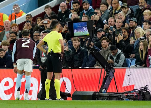 Birmingham, England, 16th April 2026. Referee Jose Maria Sanchez reviews a potential handball before awarding a penalty during the Aston Villa vs Bologna UEFA Europa League quarter final 2nd leg match at Villa Park, Birmingham. Picture credit should read: Andrew Yates Sportimage EDITORIAL USE ONLY. No use with unauthorised audio, video, data, fixture lists, club league logos or live services. Online in-match use limited to 120 images, no video emulation. No use in betting, games or single club league player publications. SPI_035_AY_Villa_Bologna SPI-4689-0035