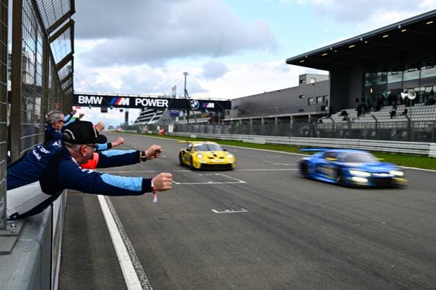 Zuschauer jubeln an der Start-Ziel-Gerade am Nürburgring, während zwei Rennfahrzeuge in Aktion sind ADAC RAVENOL 24h Nürburgring Qualifiers - 19.04.2026 NLS 5 *** Spectators cheer at the start-finish straight at the Nürburgring while two race cars are in action ADAC RAVENOL 24h Nürburgring Qualifiers 19 04 2026 NLS 5 Copyright: xSpeedshotx
