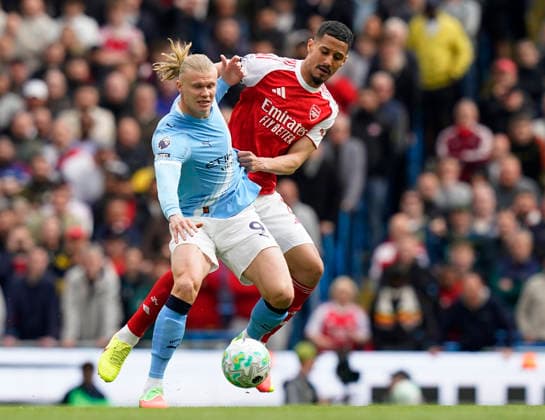 Manchester, England, 19th April 2026. William Saliba of Arsenal (l) tussles with Erling Haaland of Manchester City (r) during the Manchester City vs Arsenal Premier League match at the Etihad Stadium, Manchester. Picture credit should read: Andrew Yates Sportimage EDITORIAL USE ONLY. No use with unauthorised audio, video, data, fixture lists, club league logos or live services. Online in-match use limited to 120 images, no video emulation. No use in betting, games or single club league player publications. SPI_054_AY_Man_City_Arsenal SPI-4704-0053