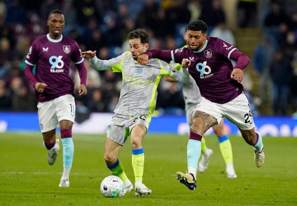 Burnley, England, 22nd April 2026. Bernardo Silva of Manchester City (C) is challenged by Josh Laurent of Burnley during the Burnley vs Manchester City Premier League match at Turf Moor, Burnley. Picture credit should read: Andrew Yates Sportimage EDITORIAL USE ONLY. No use with unauthorised audio, video, data, fixture lists, club league logos or live services. Online in-match use limited to 120 images, no video emulation. No use in betting, games or single club league player publications. SPI_034_AY_BURNLEY_MAN_CITY SPI-4716-0034