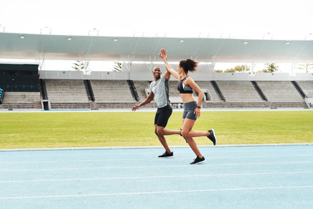 Man, woman and high five for running on track for exercise, fitness and race in stadium. Male athlete, female personal trainer and success in arena for contest, competition and achievement or victory. (License=RF) 21841686 ,model released, Symbolfoto  Copyright: xZoonar.com YURIxARCURSxPRODUCTIONSx 21841686 ,model released, Symbolfoto ,property released