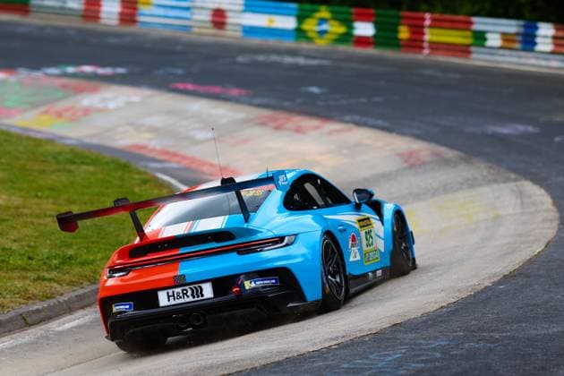 The Porsche 911 GT3 with the starting number 925 from Huber Motorsport drives through a tight curve on the Nordschleife at the Nürburgring The car Christopher Allen Hans Wehrmann Jaden Lander Jake Walker Jon Miller Jonathan Miller Robert Mau Huber Motorsport has an eye-catching blue, red and white design and carries sponsors such as H R and Michelin The characteristic colorful flags and graffiti paintings of the Nordschleife can be seen in the background Porsche 911 GT3 925 from Huber Motorsport on the Nordschleife Copyright: xspeedshotx