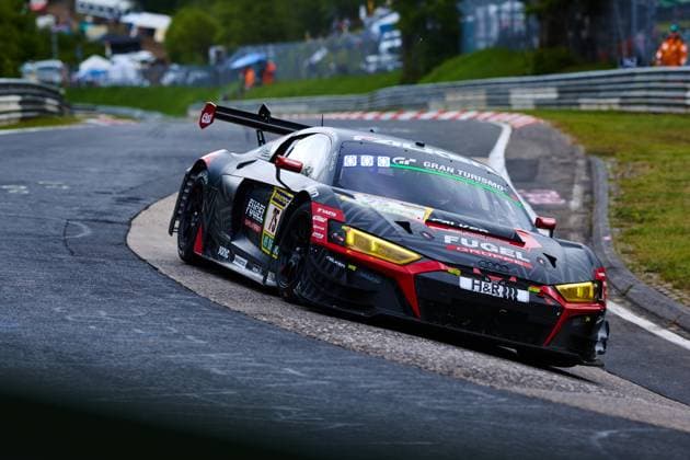 The Audi R8 LMS GT3 with starting number 75 from Falken Motorsports drives through a tight bend on the Nordschleife of the Nürburgring The dark grey Benjamin Leuchter Falken Motorsports car with striking yellow LED headlights and red color accent bears the sponsors Falken, Fugel Group and H R prominently on the bodywork Spectators and the typical vegetation of the Eifel can be seen in the background Audi R8 LMS GT3 75 from Falken Motorsports on the Nordschleife Copyright: xspeedshotx