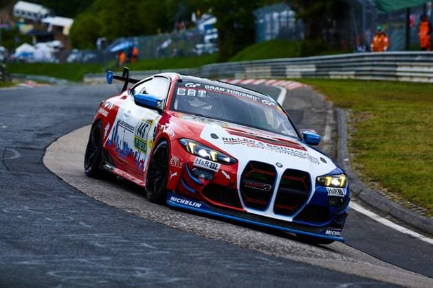 The BMW M4 with starting number 145 of the Riller Schnauck powered by Cerny Motorsport team drives through a tight bend on the Nordschleife of the Nürburgring The car Aris Balanian Jeroen Bleekemolen Joshua Bednarski Peter Cate Tom Schütze Riller Schnauck powered by Cerny Motorsport presents itself in an eye-catching red, white and blue design with sponsors such as H R. Michelin and Gran Turismo on the bodywork, Michelin and Gran Turismo on the bodywork In the background, track marshals and the characteristic crash barriers of the Nordschleife can be seen BMW M4 145 from Riller Schnauck powered by Cerny Motorsport at the Nürburgring Copyright: xspeedshotx