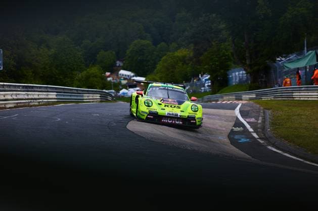 The neon yellow Porsche 911 GT3 R with the starting number 911 of the Manthey team drives through a tight bend on the Nordschleife at the Nürburgring The car Ayhancan Güven Kevin Estre Thomas Preining Manthey bears the striking sponsors KÜS, Motul, Red Bull, Veltins and H R and is adorned with Gran Turismo lettering In the background, marshals in orange clothing and spectators can be seen at the side of the track Manthey Porsche 911 GT3 911 on the Nordschleife at the Nürburgring Copyright: xspeedshotx