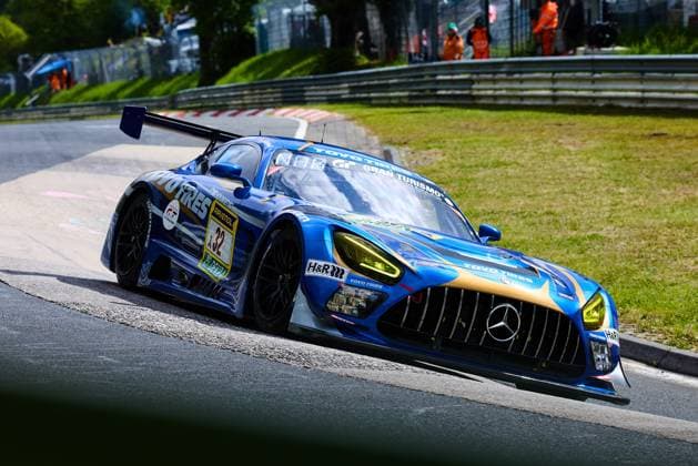 The Mercedes AMG GT3 with starting number 32 of the Toyo Tires with Ring Racing team drives through a curve on the Nürburgring The vehicle Andreas Gülden Tim Sandtler Yuichi Nakayama Toyo Tires with Ring Racing presents itself in a striking blue and gold color design with sponsors such as Toyo Tires, RAVENOL, H R and Gran Turismo In the background, track marshals in orange work clothes can be seen Mercedes AMG GT3 32 from Toyo Tires with Ring Racing on the Nürburgring Copyright: xspeedshotx