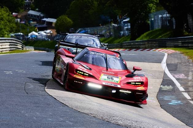The red Lamborghini Huracán GT3 with starting number 66 from Reiter Engineering drives through a tight corner on the Nordschleife of the Nürburgring The car Arne Hoffmeister Julien Apotheloz Laurents Hörr Marcel Marchewicz Miklas Born Reiter Engineering carries the sponsors RAVENOL, DEKRA, H R and Gran Turismo and is on the road with daytime running lights switched on Another vehicle can be seen in the background, while spectators and hospitality tents enliven the backdrop of the Eifel race track Lamborghini Huracán GT3 66 from Reiter Engineering on the Nordschleife Copyright: xspeedshotx