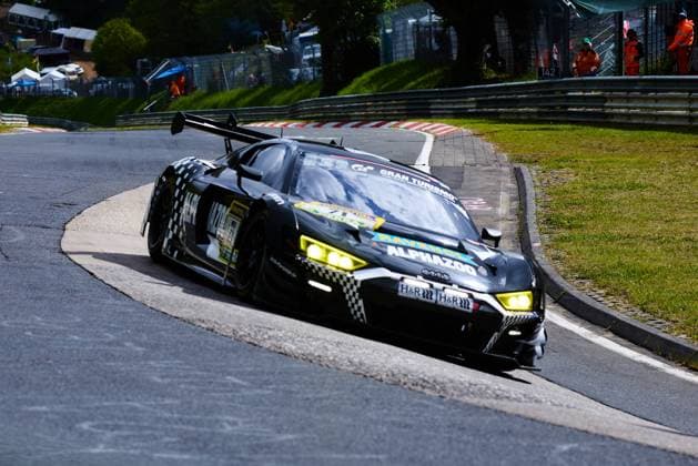 The black Audi R8 GT3 with the starting number 444 from Adrenalin Motorsport Team Mainhattan Wheels drives through a tight corner on the Nordschleife at the ADAC RAVENOL 24h Nürburgring 2026 The car in the striking checkerboard design bears the sponsors Alphazoo, RAVENOL, H R and Gran Turismo and takes the bend with its headlights switched on In the background, track marshals in orange safety clothing and mile marker 142 can be seen 444 Womens national soccer team Poland Audi R8 GT3 444 from Adrenalin Motorsport in the Nordschleife bend Copyright: xspeedshotx