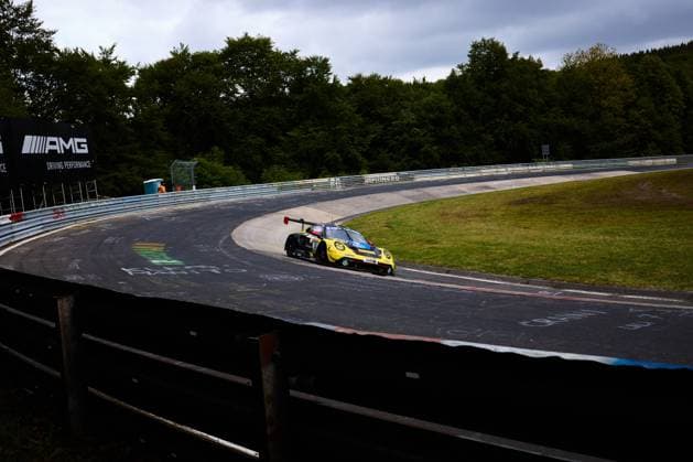 The yellow and black painted Porsche from Reiter Engineering drives through a characteristic curve of the Nordschleife at the Nürburgring The AMG banner with the lettering Driving Performance can be seen in the background The vehicle with the starting number 91 takes the curve on the well-known demanding course in the Eifel racing car Yellow and black Porsche 91 from Reiter Engineering in the Nordschleife curve Copyright: xspeedshotx