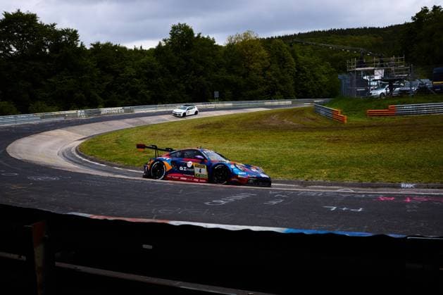 The Porsche 911 GT3 with starting number 4 of the Goroyan RT by Car Collection team drives through a bend on the Nordschleife at the Nürburgring The vehicle Alex Fontana Artur Goroyan Nathanael Berthon Oleg Kivtka Oleg Kvitka Goroyan RT by Car Collection wears a striking blue, red and orange livery with sponsors GInvest and SRT. eye-catching blue, red and orange livery with the sponsors GInvest and SRT The characteristic layout of the Nordschleife with crash barriers and green areas can be seen in the background Porsche 911 GT3 4 from Goroyan RT by Car Collection on the Nordschleife Copyright: xspeedshotx